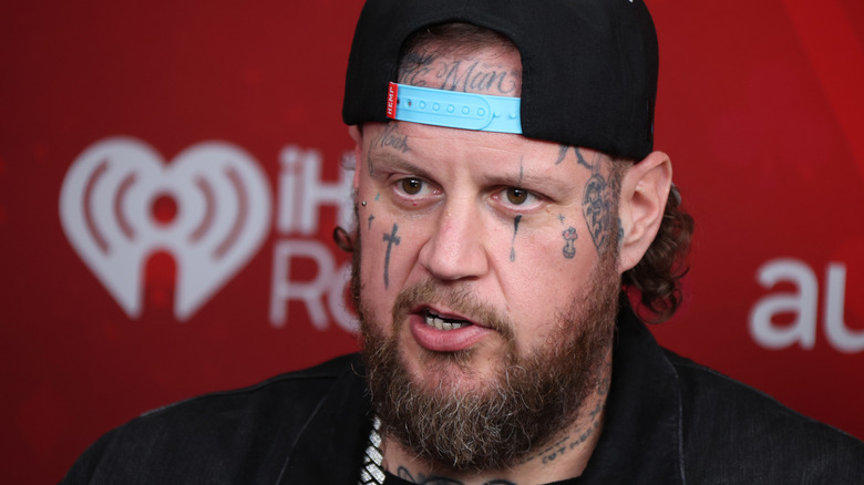 Jelly Roll looking serious wearing backwards cap