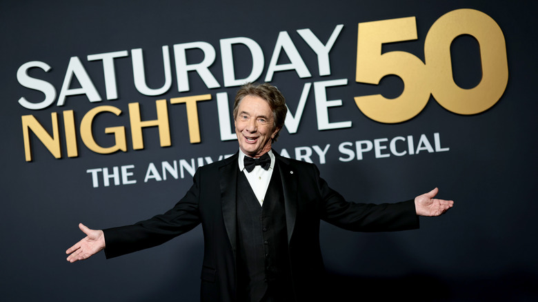 Martin Short in a tuxedo stretches his arms at the 