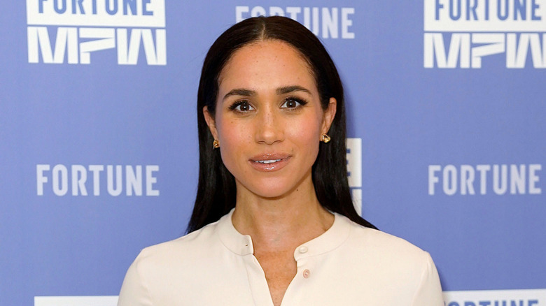 Meghan Markle posing in a white top