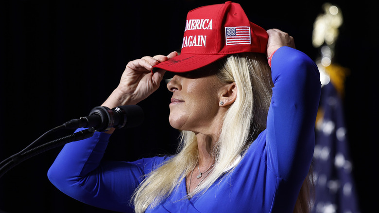 Marjorie Taylor Greene (R-GA) puts on her Make America Great Again hat while addressing a campaign rally in March 2024
