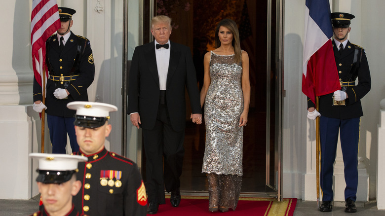 Melania Trump wearing Chanel while entering a state dinner hand in hand with a tuxedoed President Donald Trump