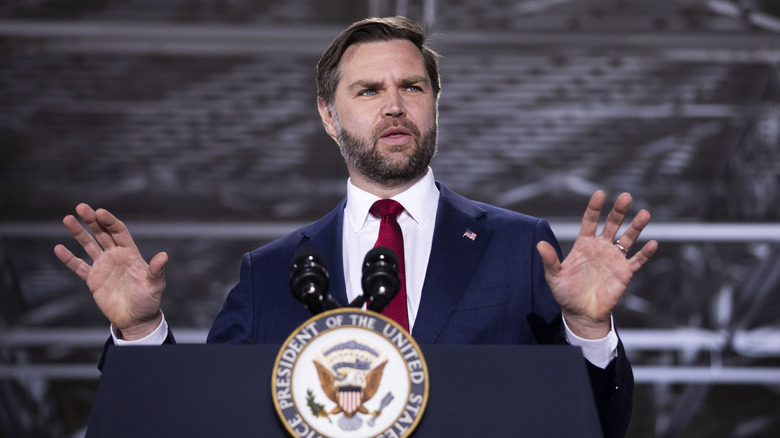 JD Vance speaking while squinting his eyes and holding his hands up.