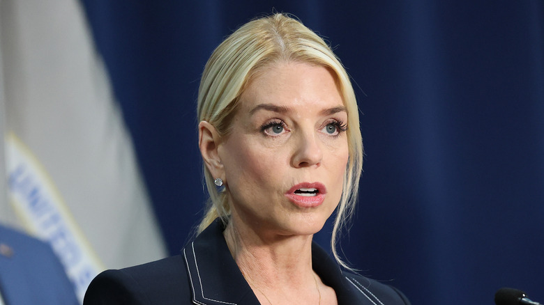 Pam Bondi mouth open as she speaks in a black blazer with white trim