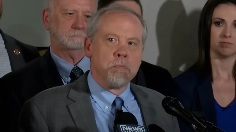 Creighton Waters speaking into a microphone at a press conference